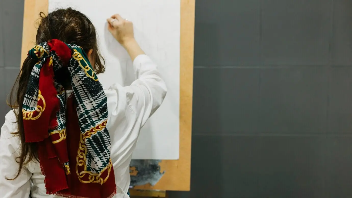 Yüzü görünmeyen, şövale üzerinde çizim yapan kadın